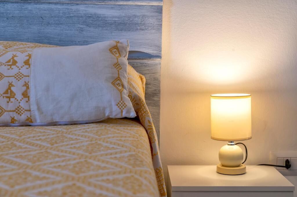 A bed with patterned bedding, a bedside lamp, and a wooden headboard.