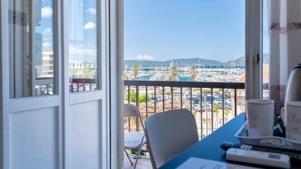 A balcony with a view of a marina and distant hills. - algherohorizon (Alghero)