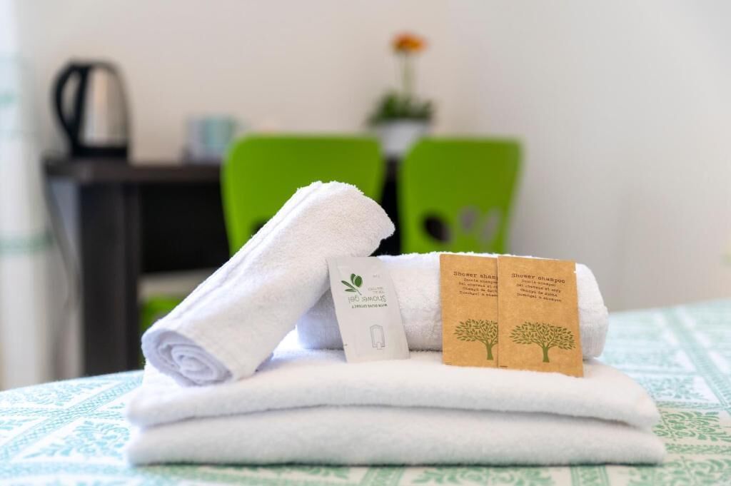 Una toalla blanca doblada con dos etiquetas marrones sobre una cama con una colcha verde y blanca estampada.