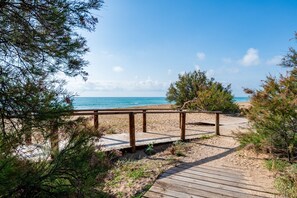 A wooden boardwalk leading to a beach with clear skies and calm sea. - 'Turquoise Blue' Studio with Sea View, Wi-Fi, and Air Conditioning (Peñíscola)
