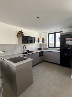 Una cocina moderna con una isla central, electrodomésticos integrados y un amplio ventanal que proporciona luz natural.