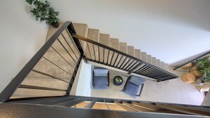 Uma escadaria leva a um espaço de estar com uma mesa e cadeiras.