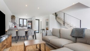 A modern living room with a sofa, coffee table, and dining area with chairs. - Holiday Home 'Salitre y Lava' with Shared Pool and Private Terrace (Corralejo)