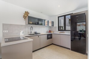 A modern kitchen with a built-in oven, a sink, and a window.