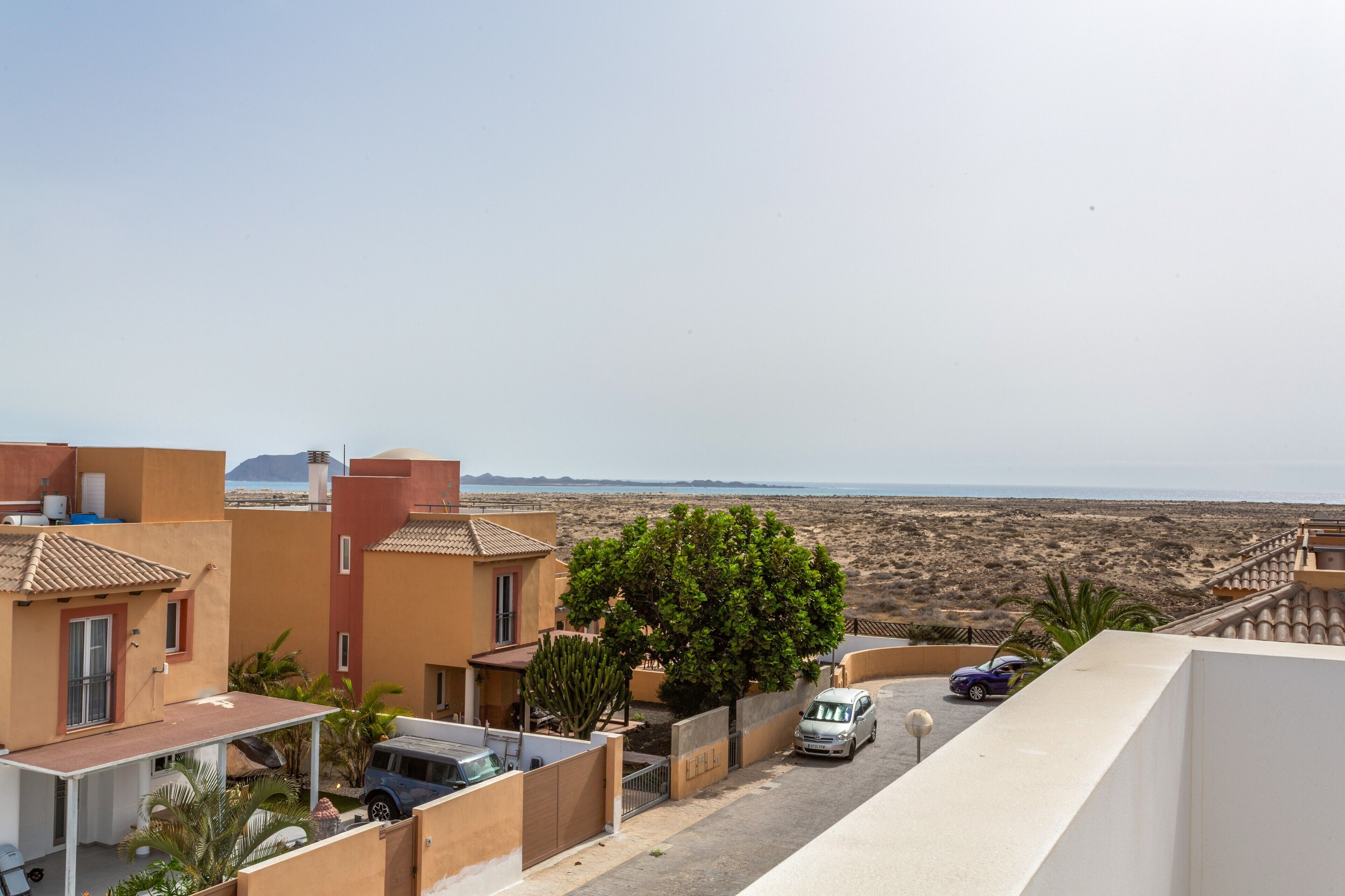 Zona residencial con casas, un árbol y vistas a la playa.