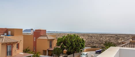 Zona residencial con casas, un árbol y vistas a la playa.