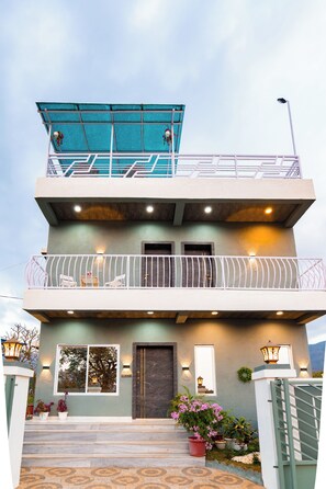 A multi-story building with a balcony, steps leading to the entrance, and outdoor lighting. - Soulskape by Alaya Stays 4-BHK Villa (Karjat)