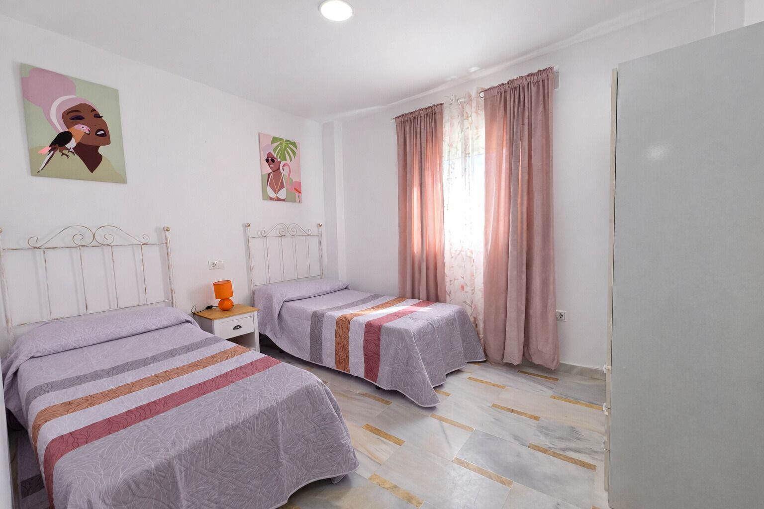 Una camera da letto con due letti, un comodino e una finestra con tende.