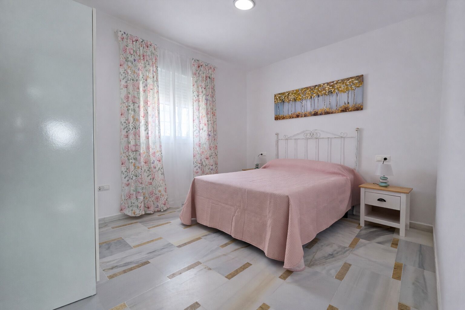 Une chambre à coucher avec un lit, une table de chevet, un tableau et une porte.