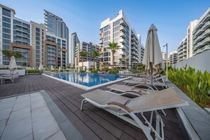 A modern hotel with a swimming pool, sun loungers, and high-rise buildings in the background. - Free housekeeping visits during your stay - Peaceful Studio for 2 in Meydan! (Meydan)