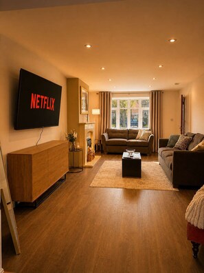 Ein Wohnzimmer mit Flachbildfernseher, Kamin, zwei Sofas und einem Couchtisch.