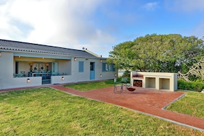 A modern house with a patio, a dining area, and a large tree. - De Mond Villa (Overberg)