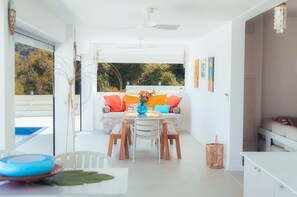 A bright, open-plan living area with a dining table, sofa, and ceiling fan. - Villa Macatia - 200m from the beach (Saint-Paul)