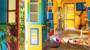 Un pasillo colorido con suelo de baldosas, una puerta roja y una pared amarilla.