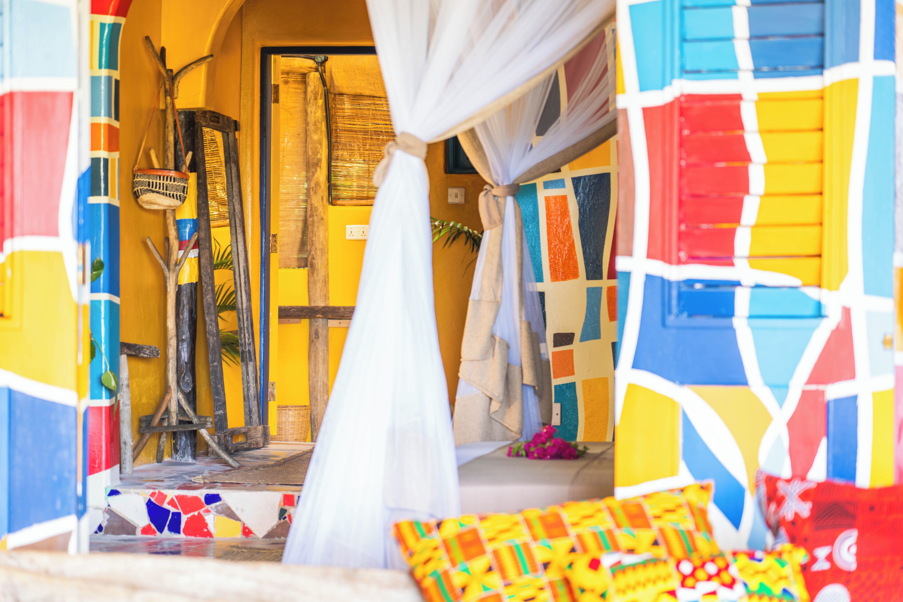 A colorful room with a bed, a curtain, and a wall with a geometric pattern.