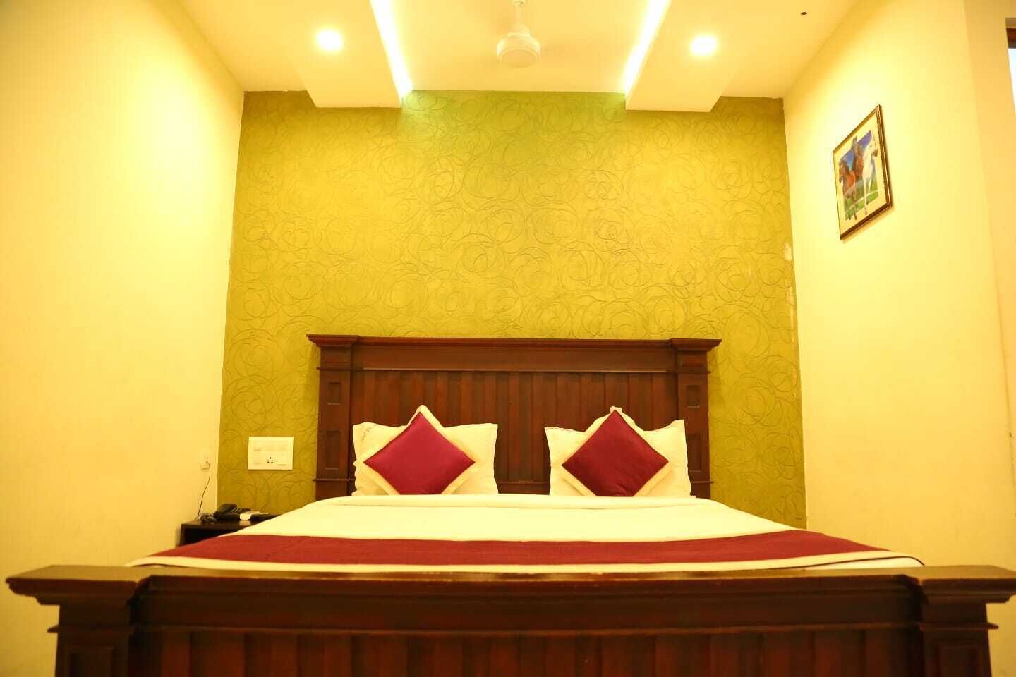 Un dormitorio con una cama de madera, una pared verde con textura y un aplique de techo.