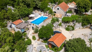 Vista aérea de una propiedad con piscina, edificios de piedra y vegetación exuberante.