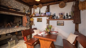 Un comedor rústico con chimenea de piedra, bancos de madera y una variedad de botellas en estanterías.