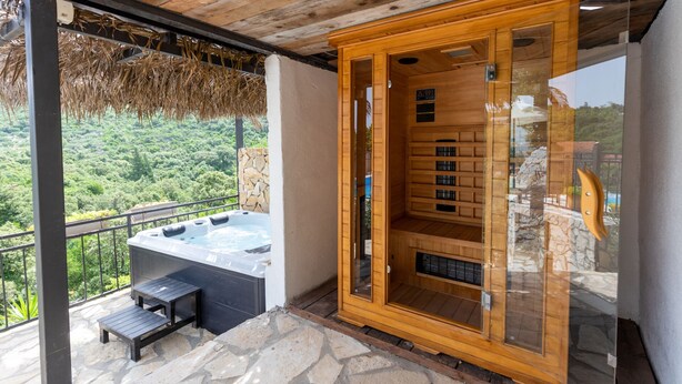 Un jacuzzi y sauna en un balcón con vistas a un bosque.