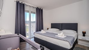 Una habitación de hotel moderna con una cama grande, un escritorio y un balcón con cortinas.