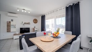 En moderne stue med spiseområde, et fjernsyn og et ur på væggen.