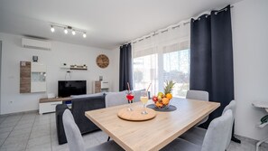 Ein modernes Wohnzimmer mit Essbereich, einem Fernseher und einer Uhr an der Wand.