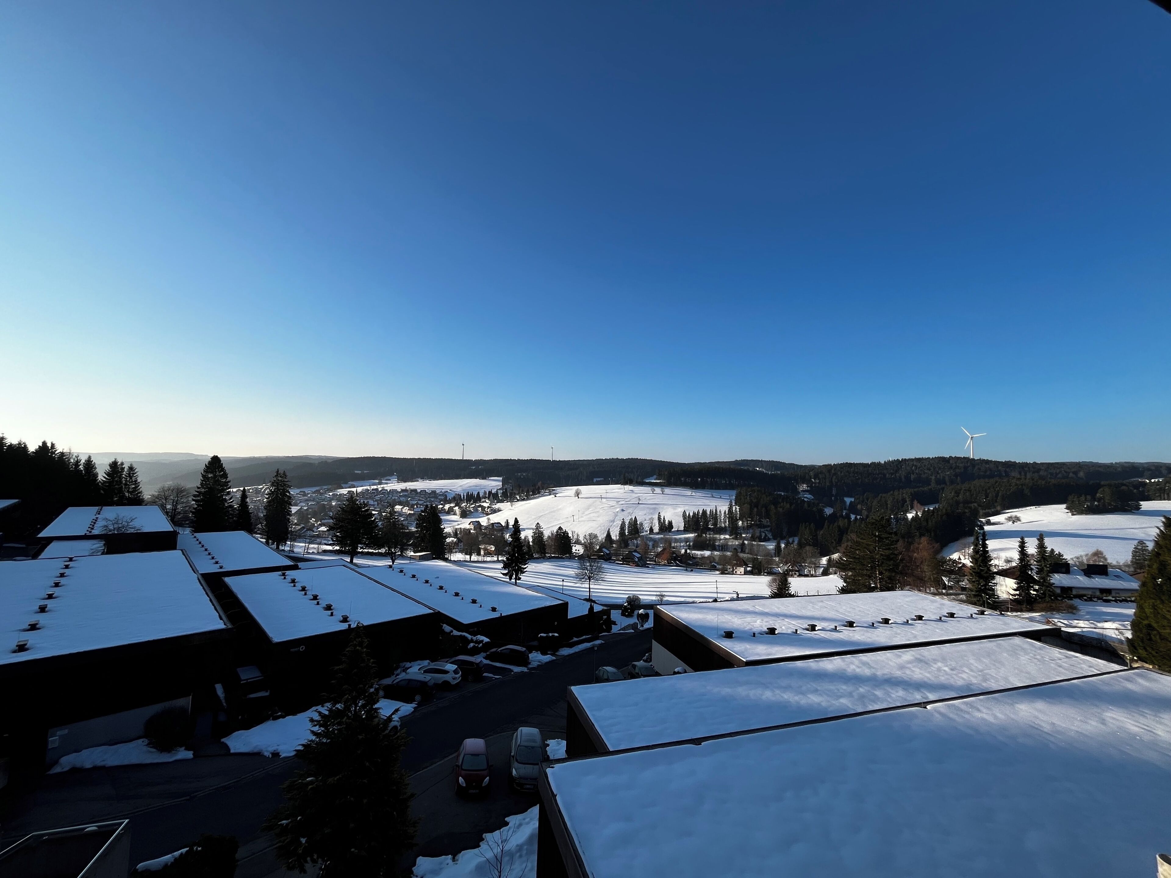 A snow-covered landscape with buildings and a wind turbine.