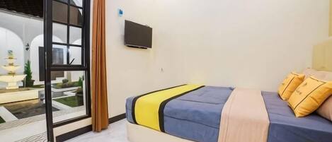 Un dormitorio con una cama, televisión y vistas a un espacio exterior.