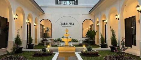 A courtyard with a fountain, arches, and a sign reading 'Riad de Alba.'