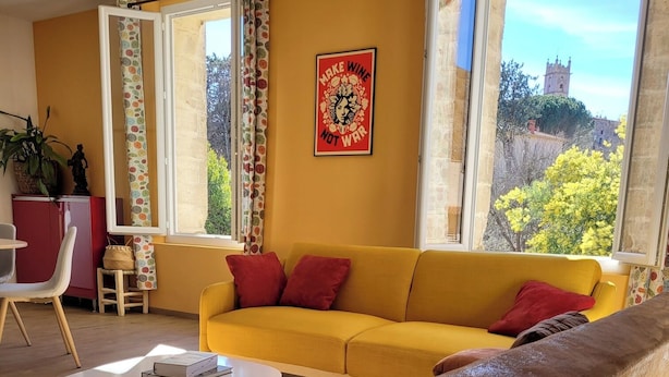 Un salon avec un canapé jaune, un fauteuil marron et une table basse blanche.