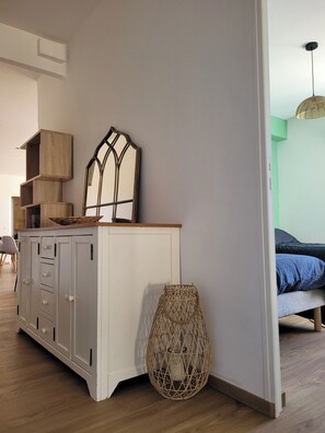 Ein Zimmer mit einem weißen Schrank, einem gewebten Korb und einem Bett mit blauer Bettwäsche.