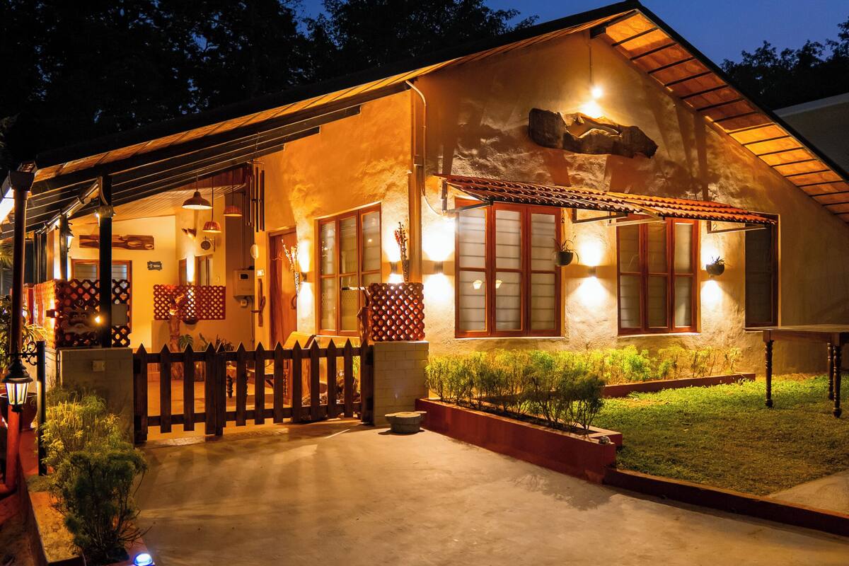 Ein Haus mit einem geneigten Dach, einem Holzzaun und einer gut beleuchteten Veranda.