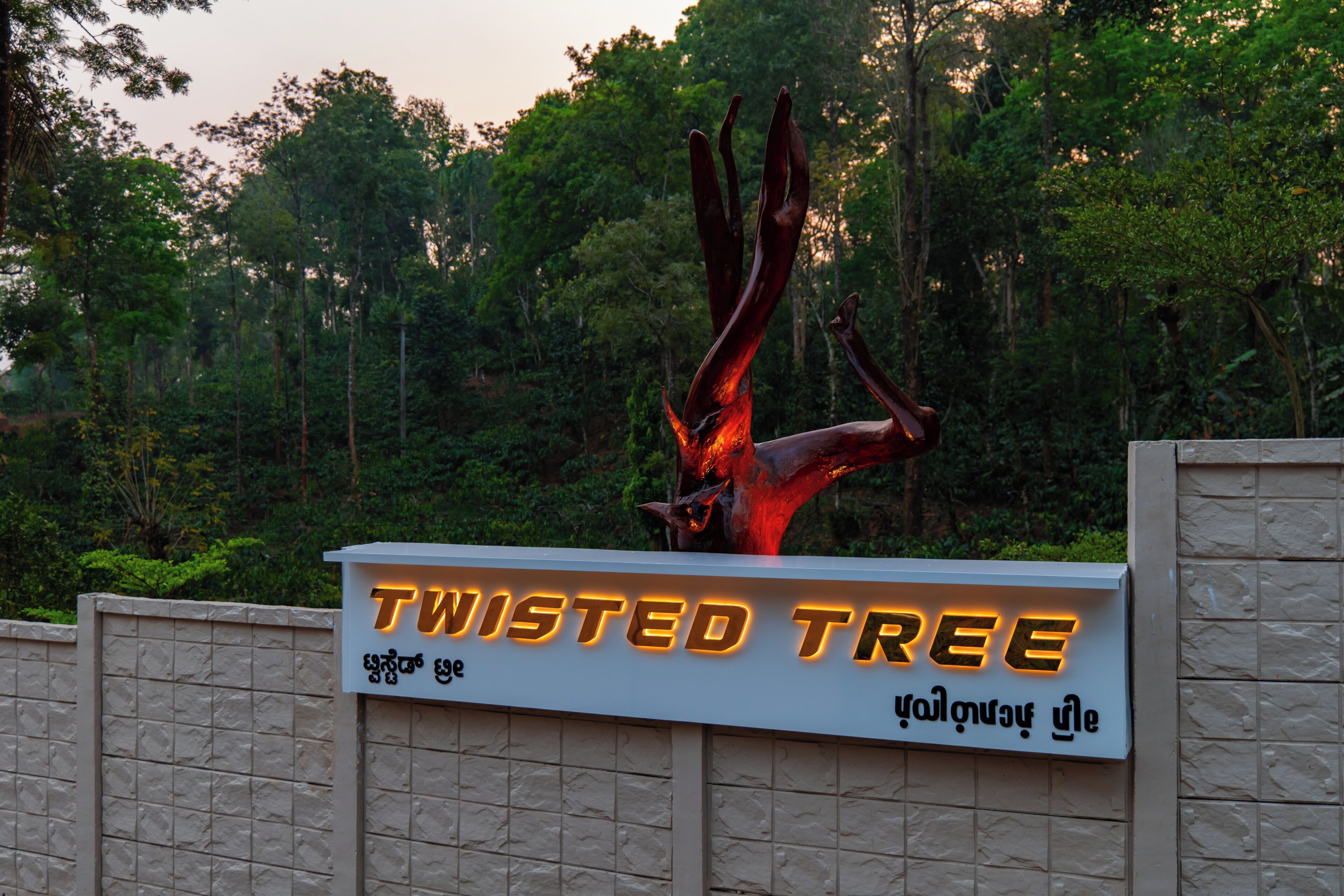 A sign for 'Twisted Tree' with a large tree sculpture above it.