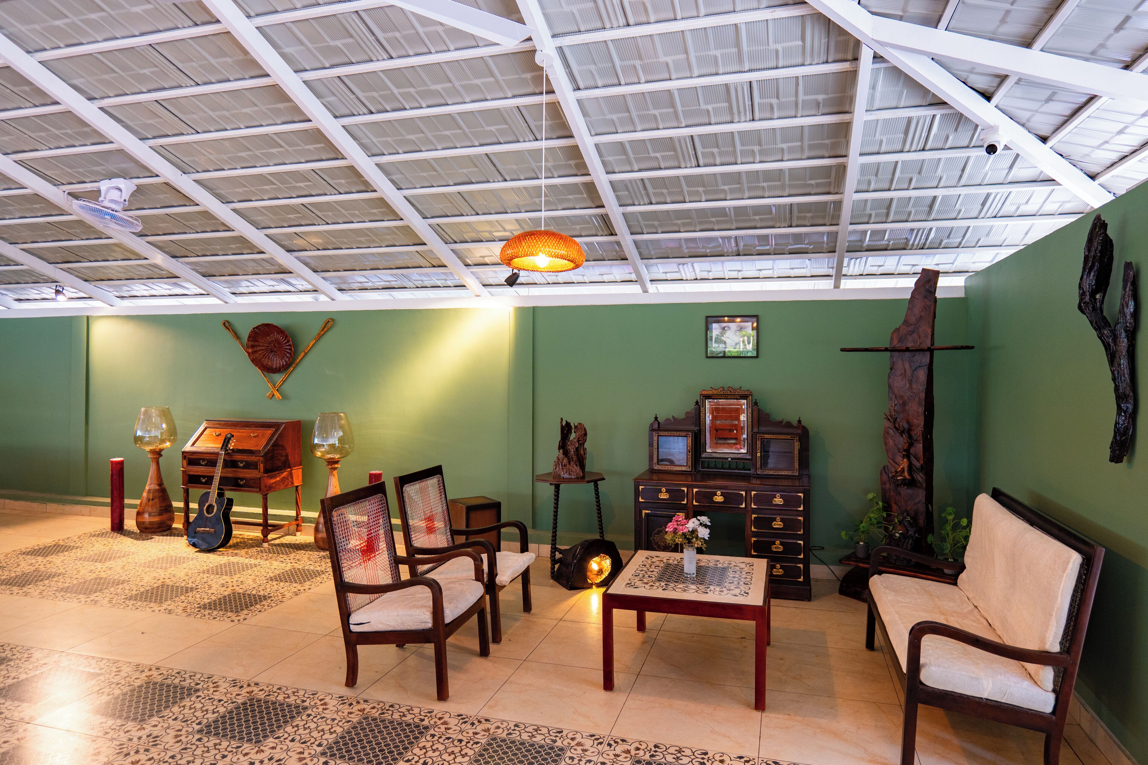 Quarto com teto alto, ventilador de teto, mesa com vaso e um armário de madeira.