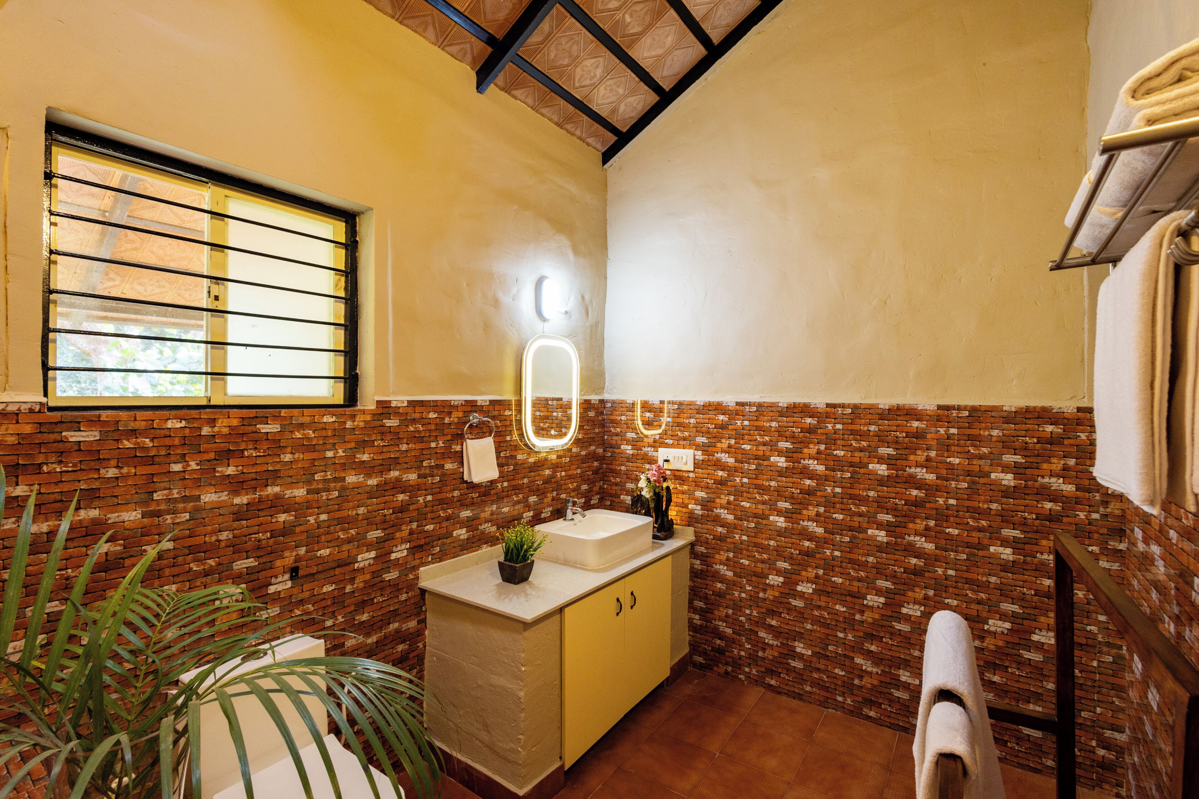 Une salle de bain avec un mur en briques, un lavabo, un miroir et un porte-serviettes.