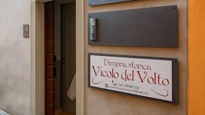A building entrance with a door, a wall-mounted sign with a number, and a business sign.