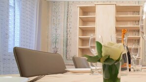 A dining table set with plates, glasses, and a vase with a white flower.