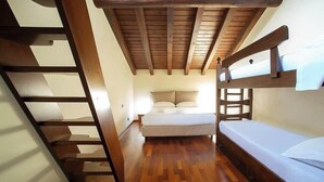 Un dormitorio con una cama litera, suelo de madera y techo inclinado.