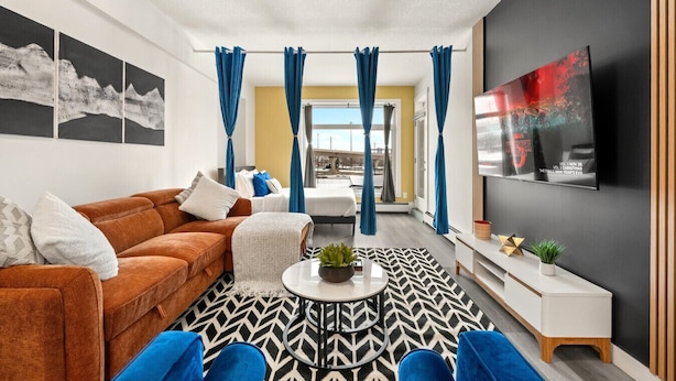 A modern living room with a sofa, coffee table, and a TV mounted on the wall. - Lux Downtown Urban Escape W/ Gym & 2 Free Parking (Calgary)