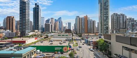 A cityscape with high-rise buildings, a parking lot, and a green building with a sign.