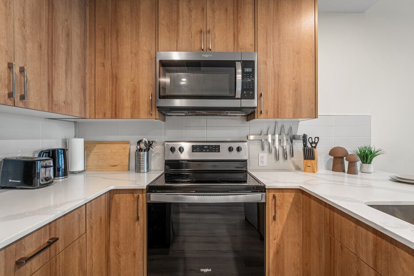 Une cuisine moderne avec des meubles en bois, un four à micro-ondes encastré, une cuisinière et un grille-pain.