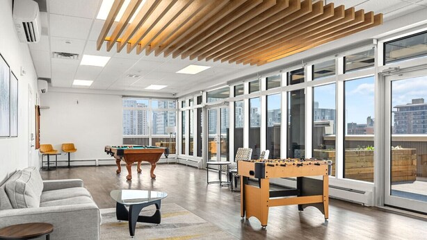 A spacious living area with a pool table, foosball table, and a sofa.