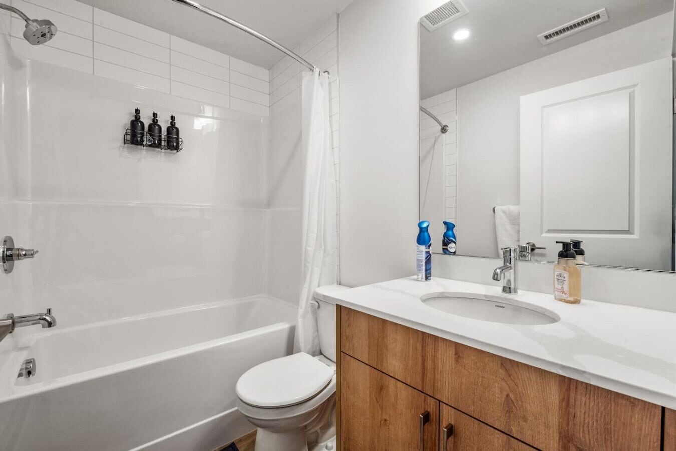 A modern bathroom with a bathtub, toilet, and vanity with a mirror.