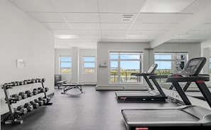 Ein Fitnessstudio mit Laufbändern, Kurzhanteln und einer Gewichtbank.