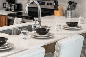 A modern kitchen with a stainless steel sink, a coffee maker, and a knife block. - Downtown Calgary Gem W / Tower Views! (Calgary)