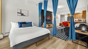 A modern hotel room with a bed, a sofa, a dining table, and a kitchen area. - Luxe Downtown Getaway W / 2 Free Parking! (Calgary)