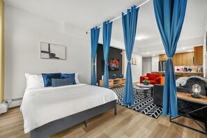 Habitació d'hotel moderna amb llit, sofà, taula de dinar i zona de cuina.