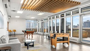 A spacious room with a pool table, foosball table, and a sofa. Large windows offer views of the city. - Luxe Downtown Getaway W / 2 Free Parking! (Calgary)