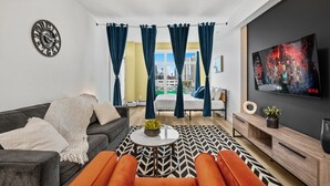 A modern living room with a sofa, armchair, coffee table, and a TV on the wall. - Luxe Downtown Getaway W / 2 Free Parking! (Calgary)