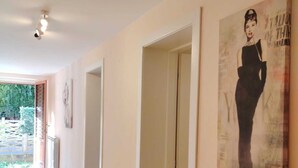 A hallway with a tiled floor, a door, and a poster on the wall. - Casa Vacanze Audrey - Porto Azzurro (Porto Azzurro)